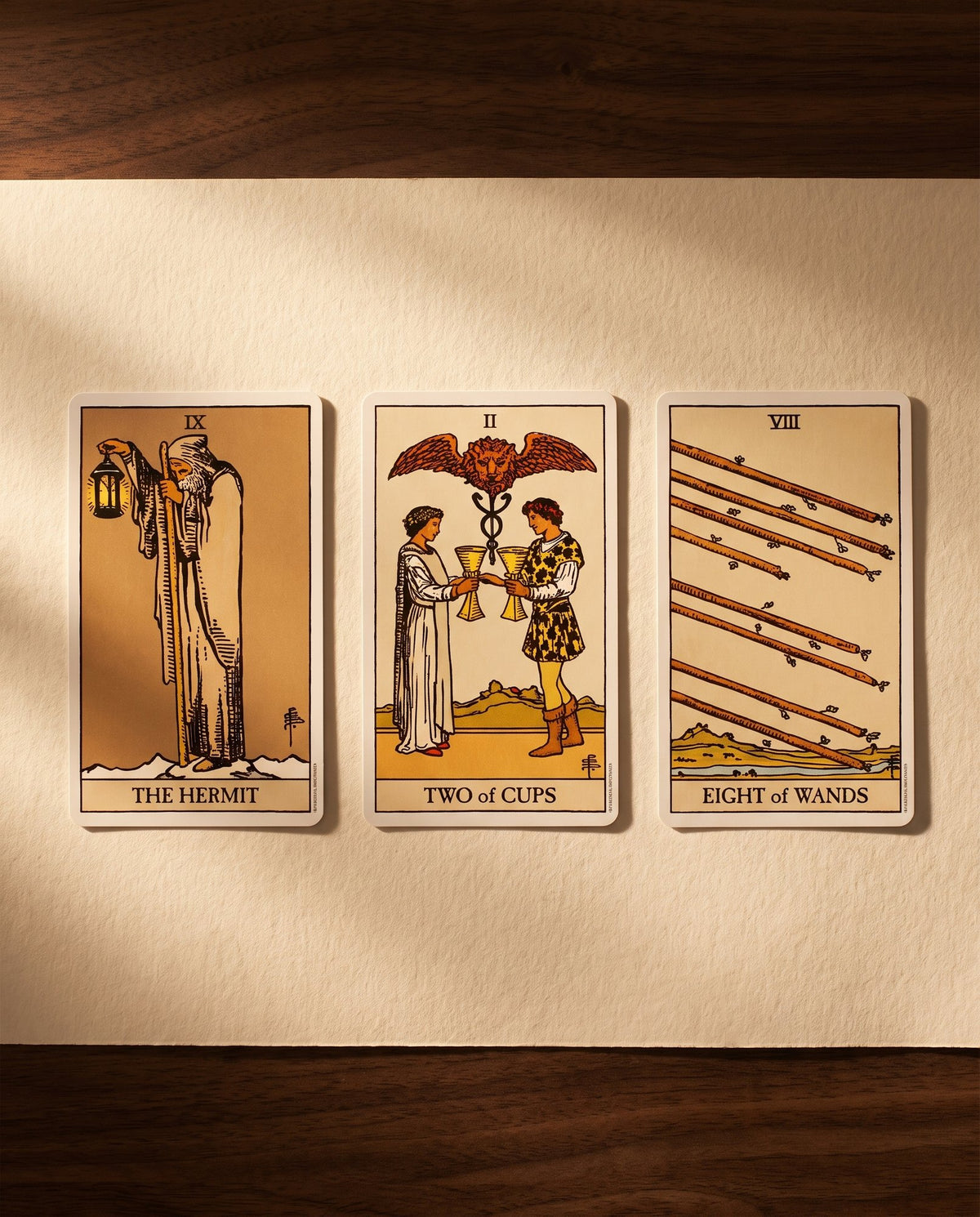 Three tarot cards laid out on paper: The Hermit, Two of Cups, Eight of Wands